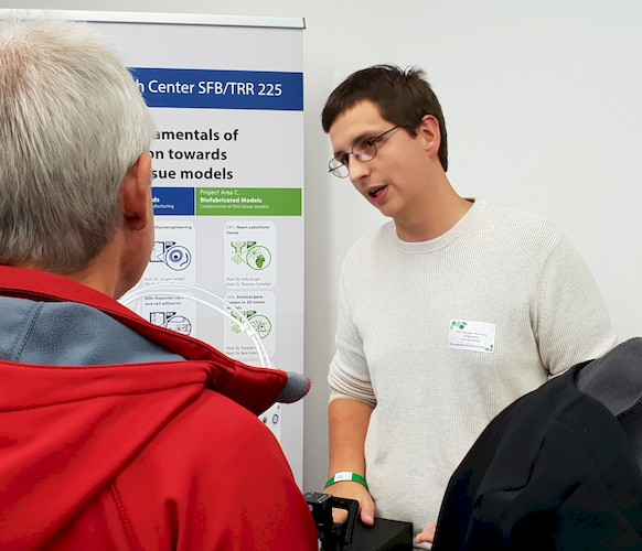 Thomas Distler erklärt einem interessierten Besucher das Thema 3D Biofabrikation.